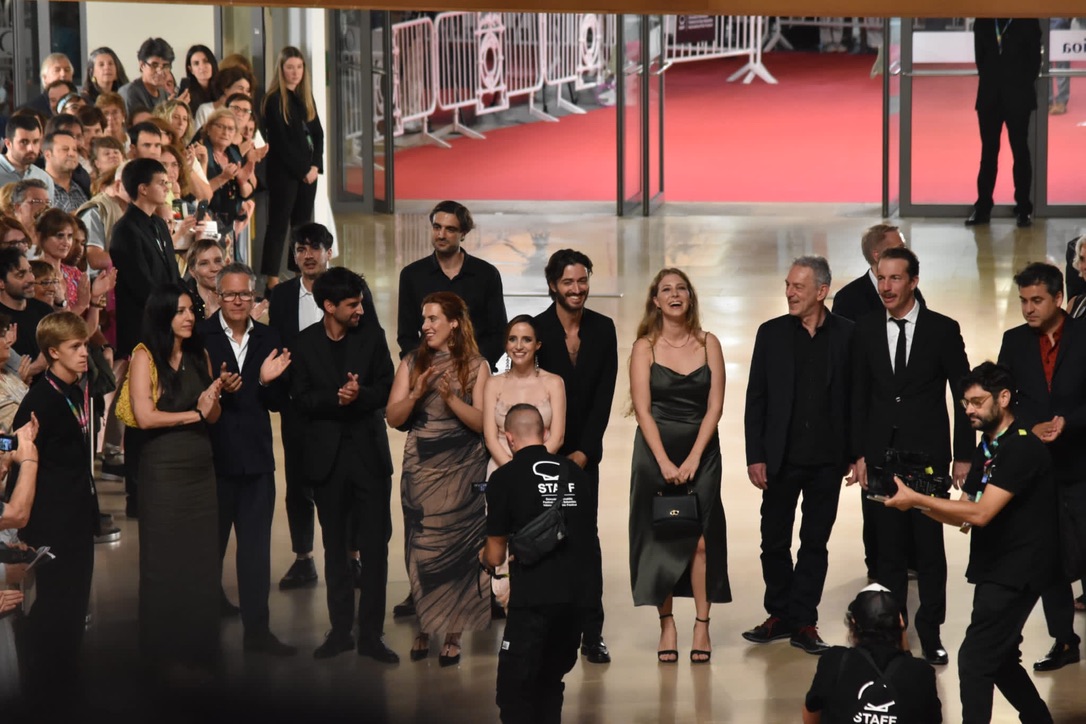 Celine Wempe with the film crew at the San Sebastián Film Festival 2023, wearing a green dress, smiling as she poses for a group photo with her team