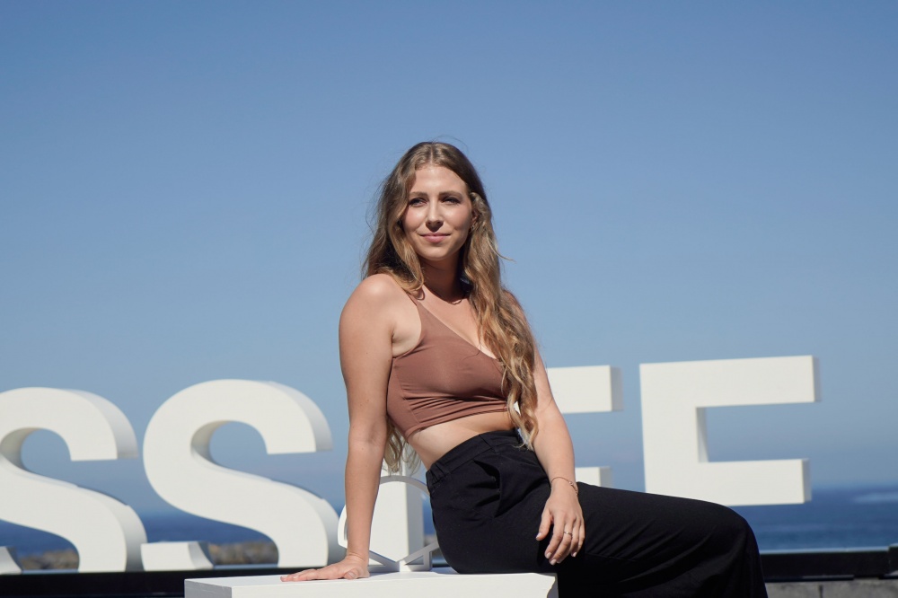 Celine Wempe during a photoshoot at the San Sebastián Film Festival 2023, wearing a brown shirt and black pants, striking a confident pose with a relaxed expression