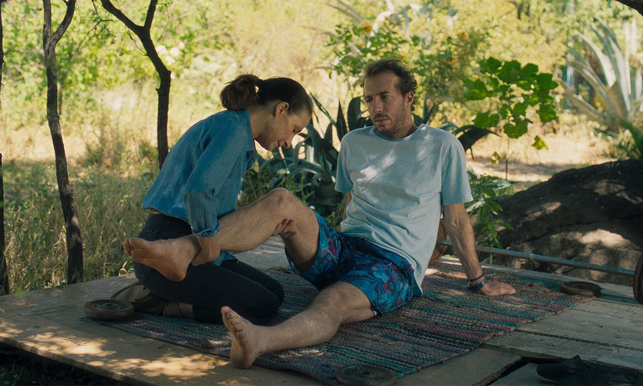 A scene from La Práctica (2023) showing a person receiving a foot massage in a relaxed setting, with the foot being gently massaged following an injury or incident, and the setting suggesting a focus on recovery and comfort.