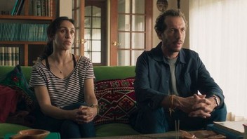 A scene from La Práctica (2023) depicting a couple therapy session, featuring a therapist and a couple seated in a counseling room, engaged in a serious conversation about their relationship."